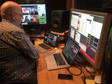A man sitting in front of several computer screens.